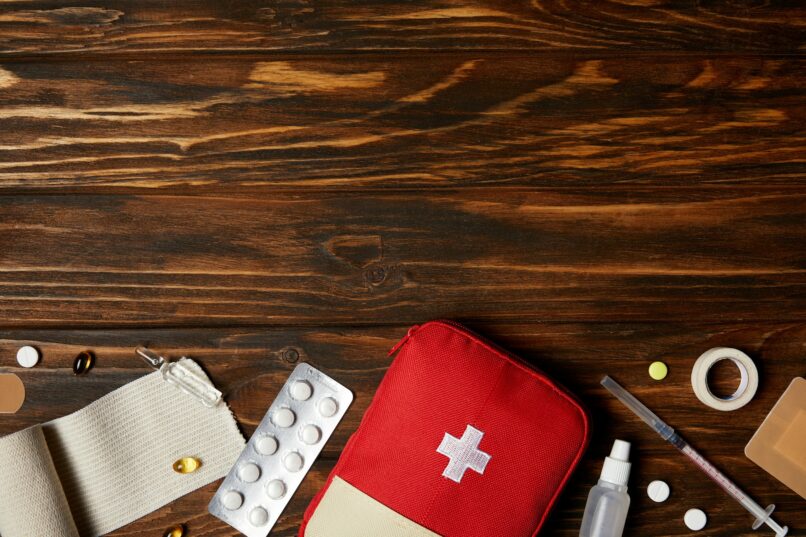 top view of first aid kit with different medicines on wooden tabletop